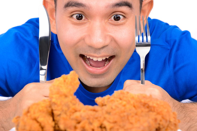 man_eating_fried_chicken_with_knife_and_fork